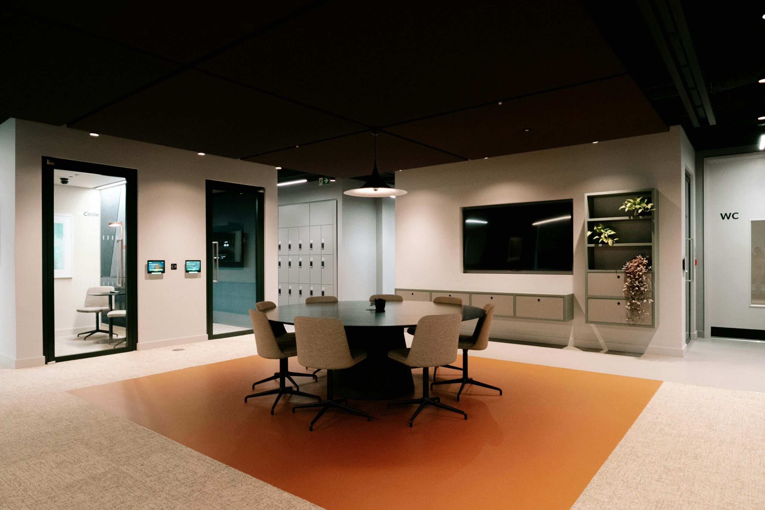 Um espaço empresarial com uma mesa e diferentes cadeiras em cima de um tapete laranja