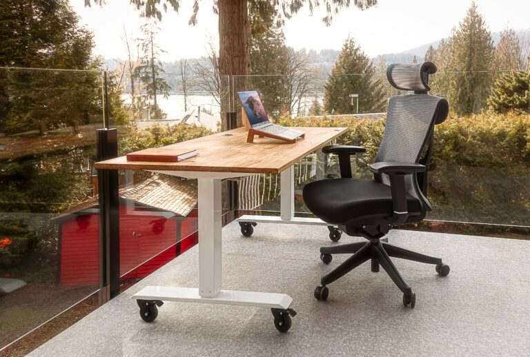 Cadeira presidente ergonômica posicionada em um escritório home office montado na sacada de uma casa, com vista para o jardim.