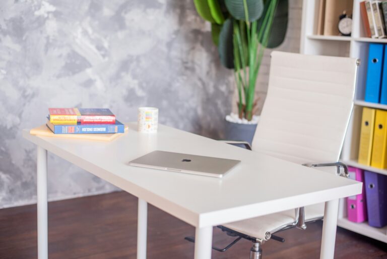 Uma mesa de estudos organizada com um laptop, livros e uma cadeira de estudos.