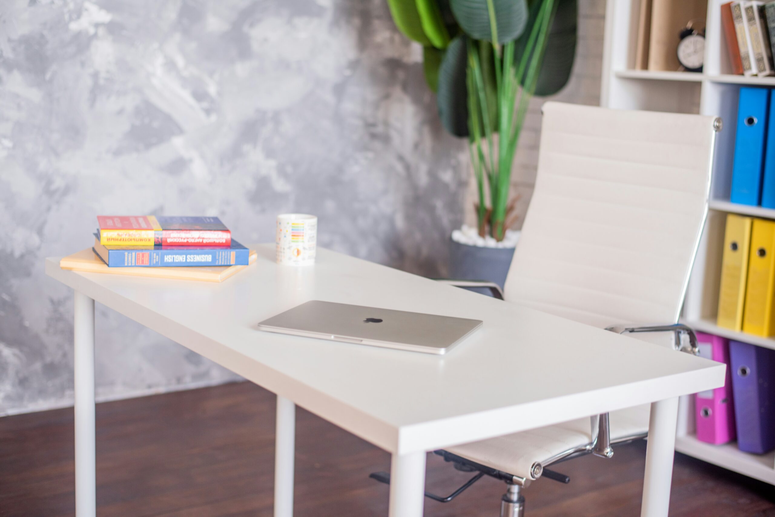 Uma mesa de estudos organizada com um laptop, livros e uma cadeira de estudos.