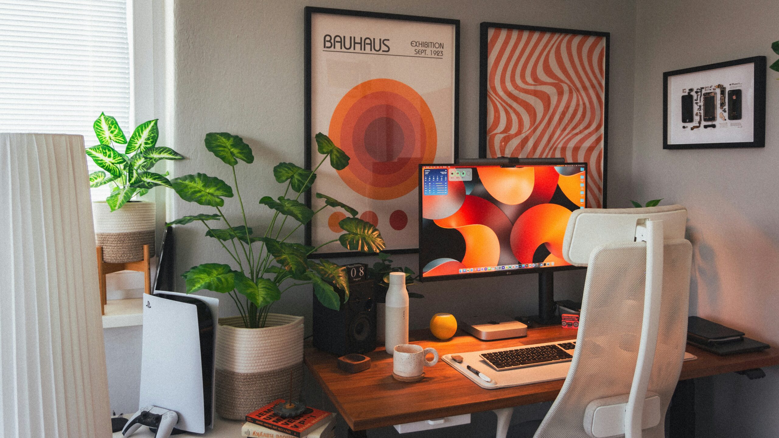 Um cantinho de estudos montado em um quarto, decorado com quadros laranjas na parede.