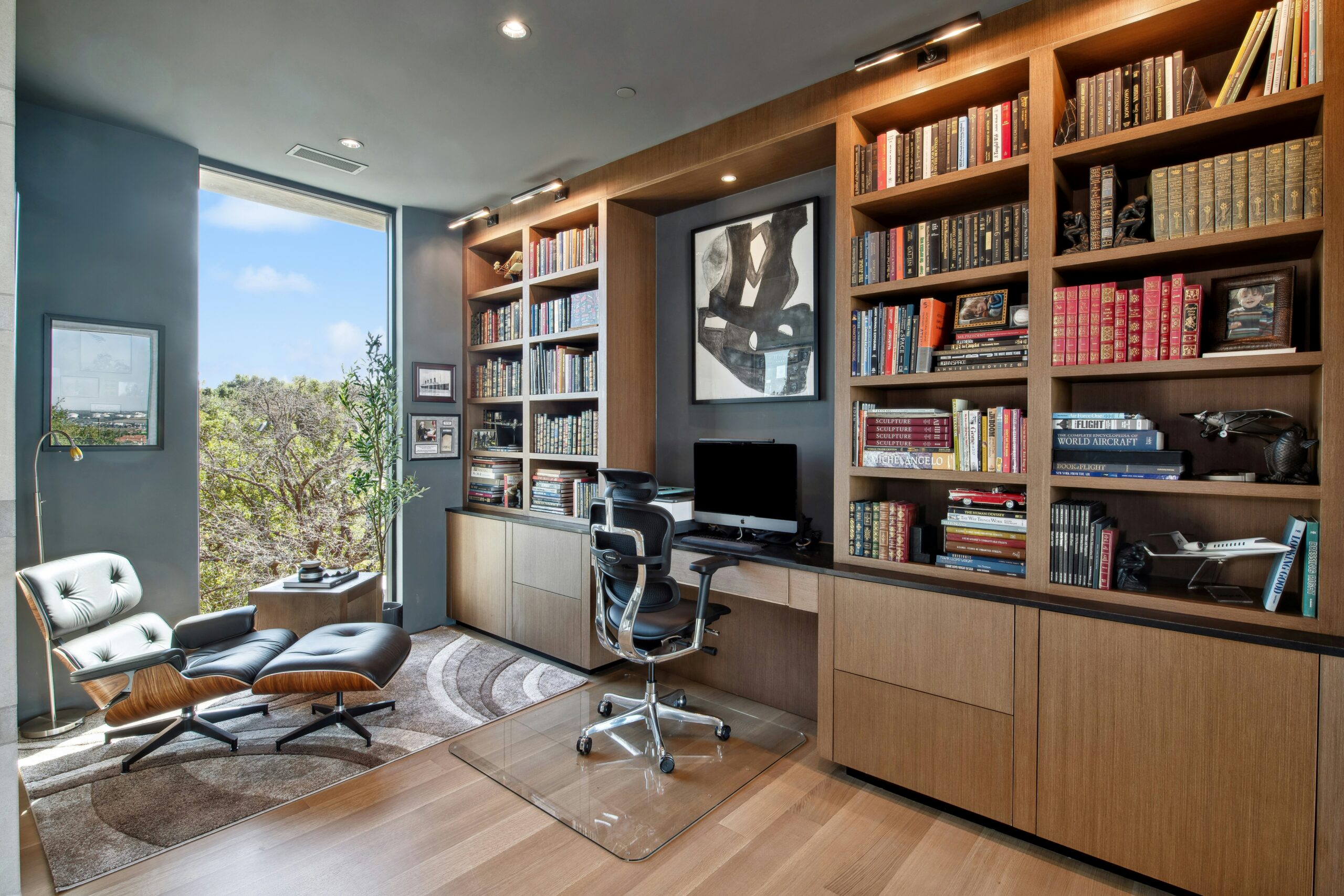 Um ambiente de home office equipado com uma biblioteca, mesa, computador e vários itens de escritório.