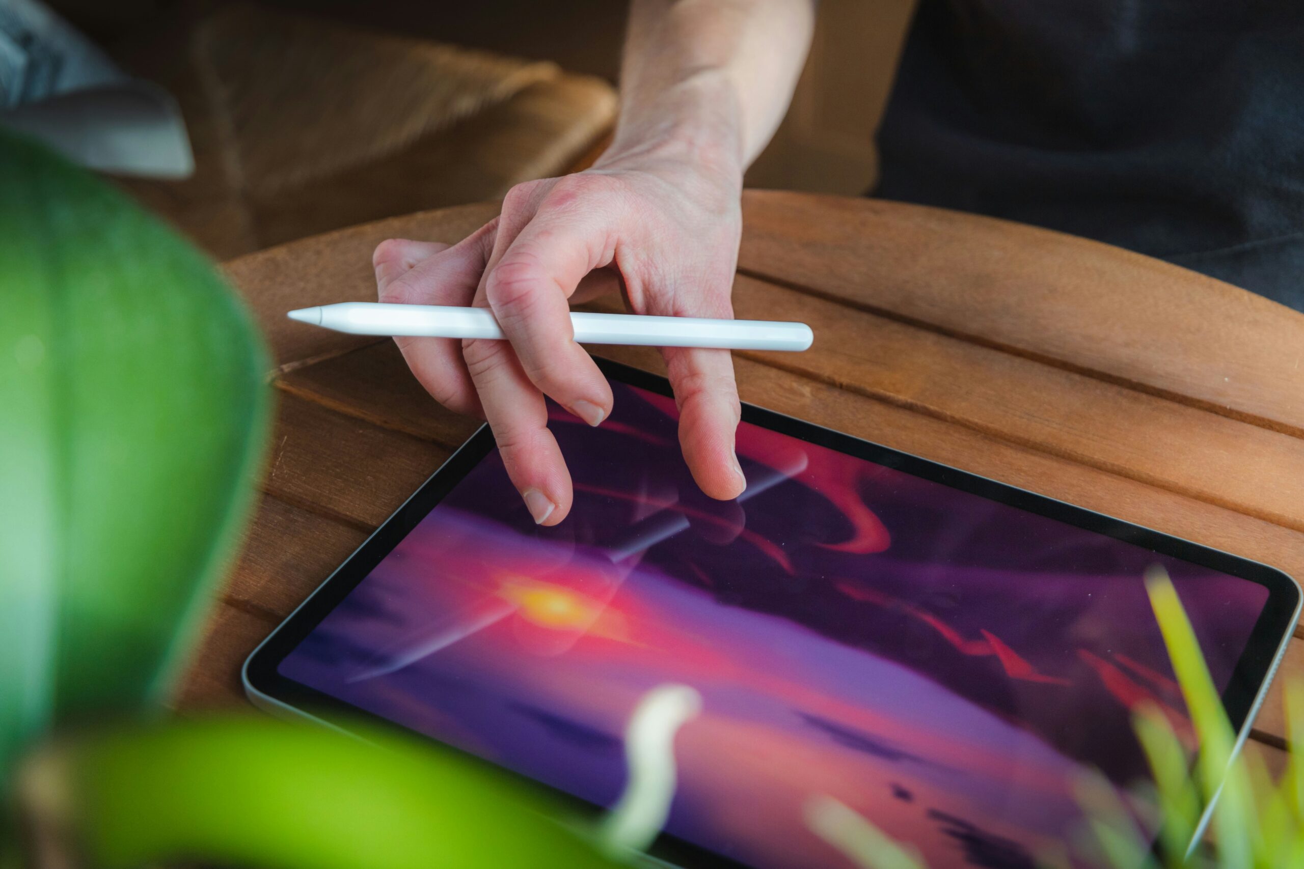 Pessoa concentrada desenhando e criando uma ilustração digital em um tablet dentro de uma cafeteria.