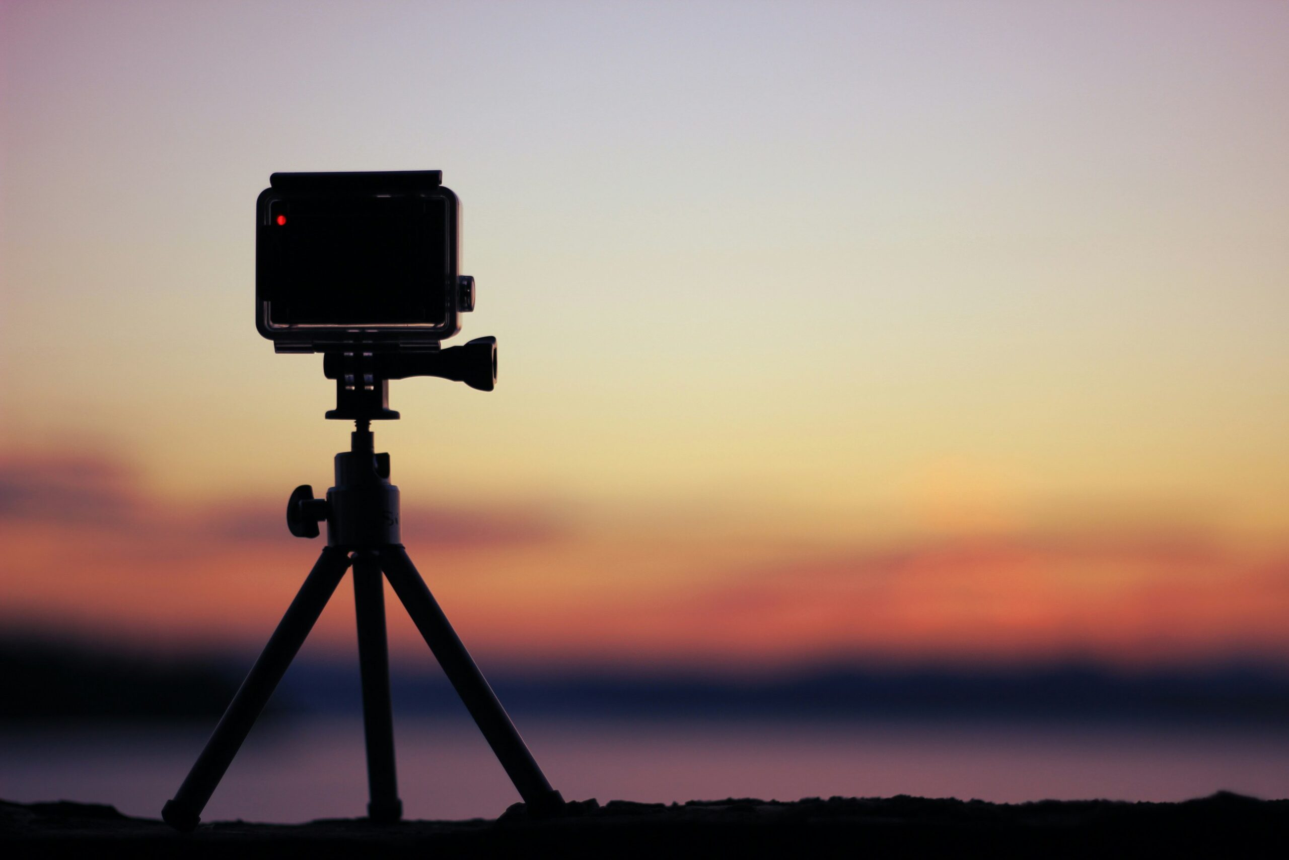 Câmera de ação apoiada na areia da praia pronta para tirar fotos e gravar vídeos à beira-mar.