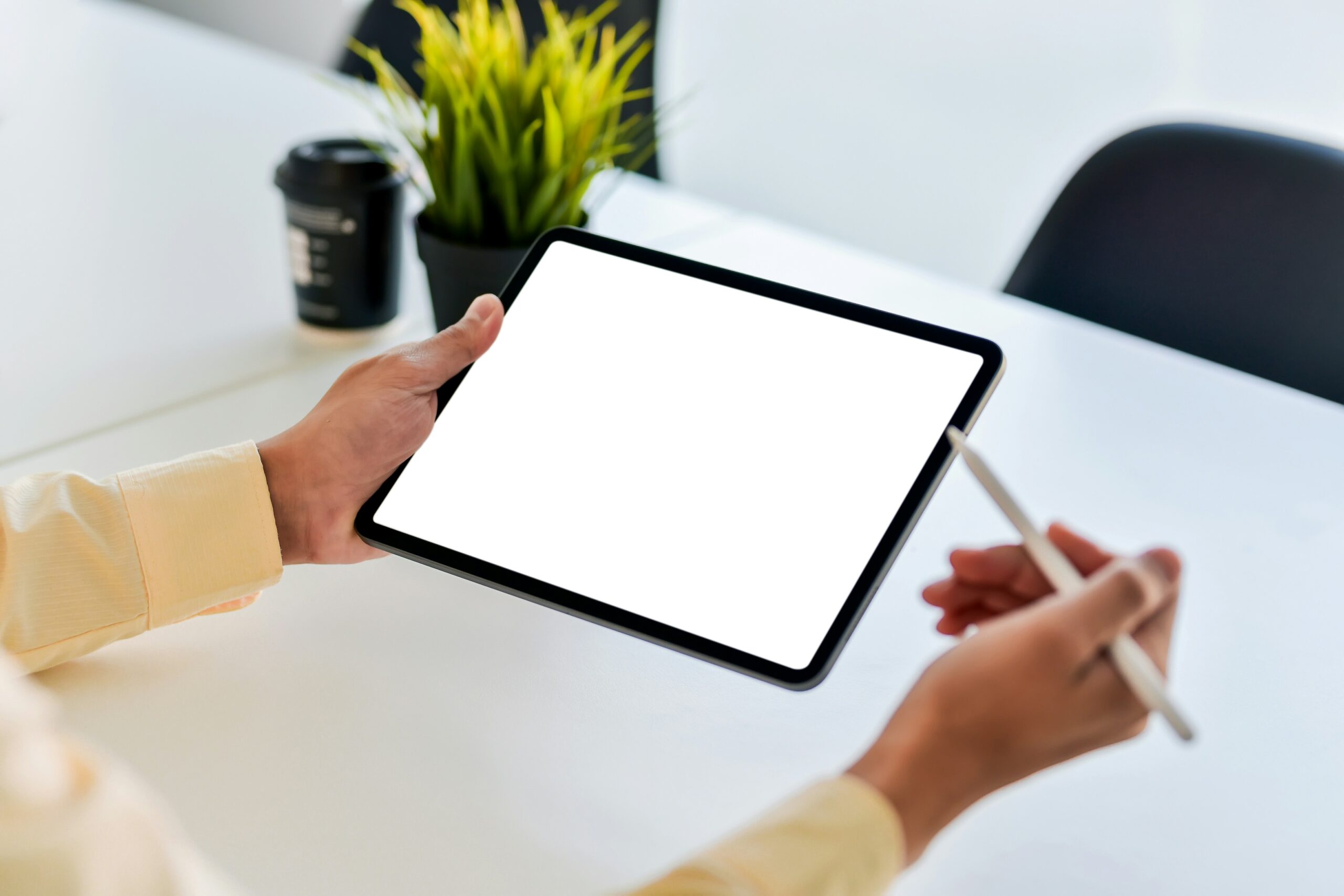 Profissional concentrado desenhando digitalmente em um tablet no ambiente de trabalho de uma empresa.